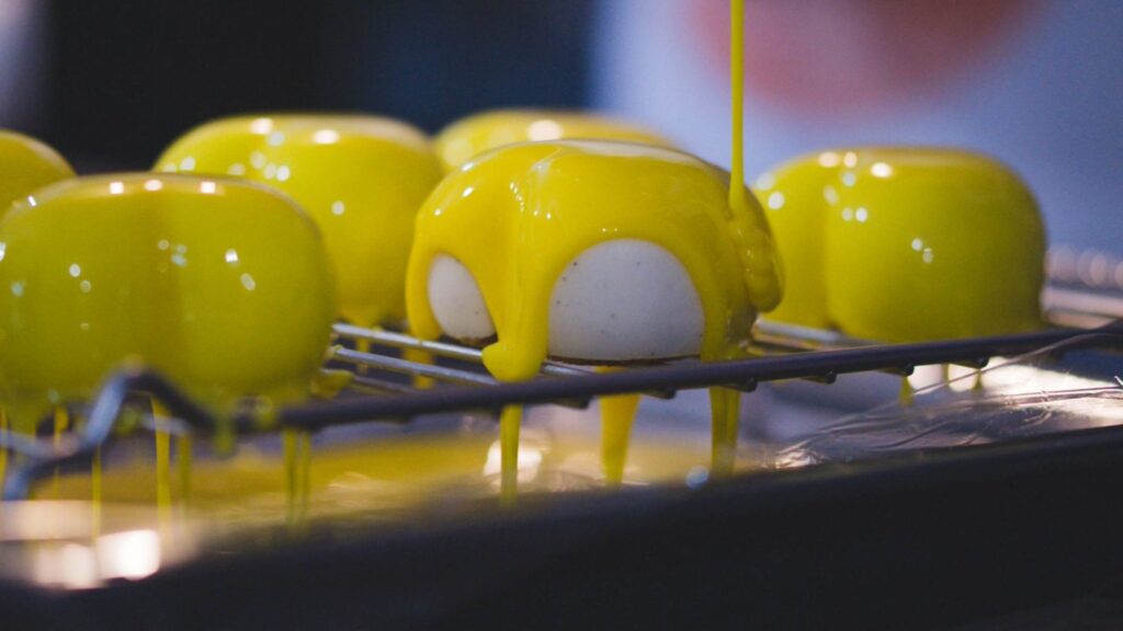 Dessert with a yellow mirror glaze on a cooling rack