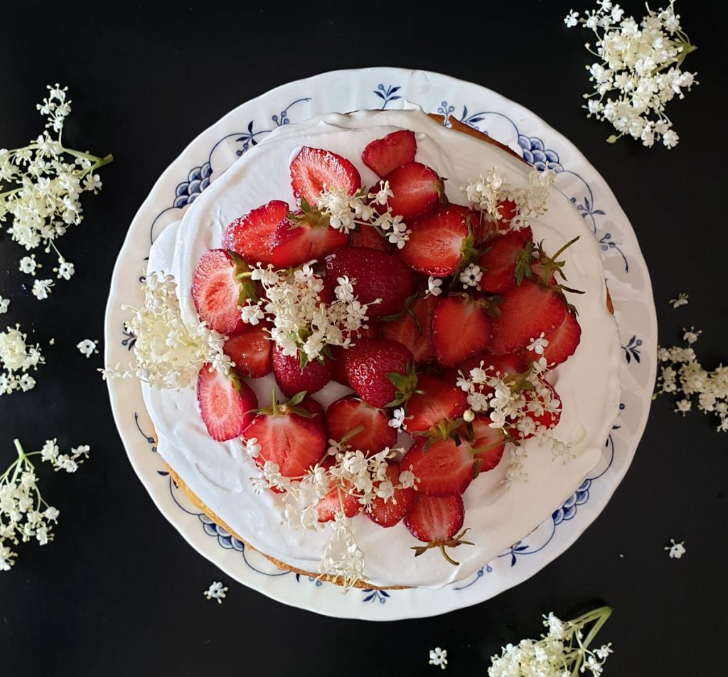 Strawberry elderflower layer cake decorated with fresh strawberries